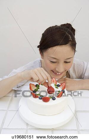 Stock Image - View of a young woman garnishing a pastry. Fotosearch