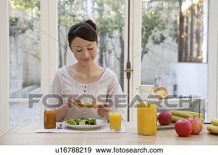 Stock Photo - View of a young woman having breakfast. Fotosearch