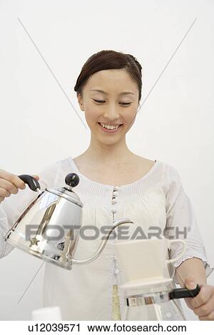 Stock Image - View of a young woman pouring from kettle. Fotosearch