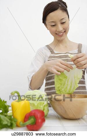 View of a young woman tearing lettuce View Large Photo Image Stock Image - View of a young woman tearing lettuce. Fotosearch