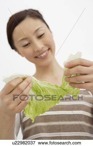 View of a young woman tearing lettuce View Large Photo Image Stock Photo - View of a young woman tearing lettuce. Fotosearch
