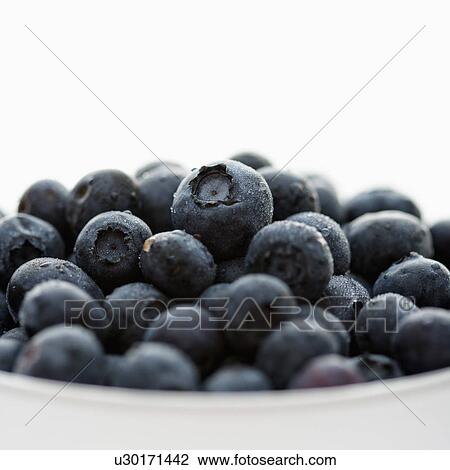Stock Image - Bowl of blueberries against white background.. Fotosearch