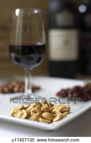 Stock Photography - Glass of red wine presented on a platter with a variety of nuts. Fotosearch