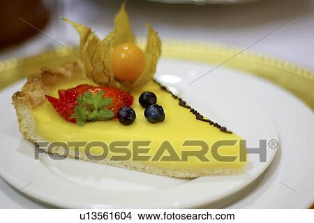 Picture - Piece of lemon fruit flan dessert on white plate. Fotosearch