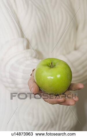 Woman holding organic apple out in front of her View Large Photo Image Stock Image - Woman holding organic apple out in front of her. Fotosearch