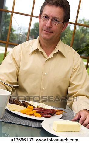 Man eating breakfast View Large Photo Image Stock Photo - Man eating breakfast. Fotosearch