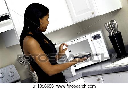 Stock Image - Woman cooking microwave meal. Fotosearch