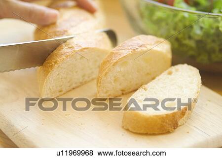 Stock Photo - Cutting bread on cutting board. Fotosearch