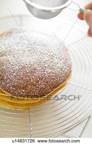Stock Photograph - Sieving sugar on pancake. Fotosearch