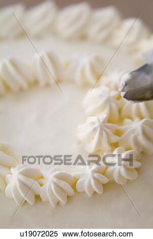 Stock Photography - Decorating a cake with whipped cream. Fotosearch