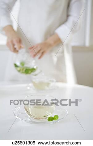 Stock Photography - Woman pouring herbal tea into cup. Fotosearch