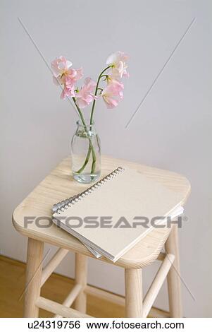 Stock Photograph - Sweet pea flowers and notebooks on stool. Fotosearch