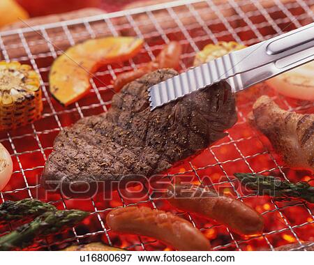 Stock Photo - Grilled beef over charcoal. Fotosearch