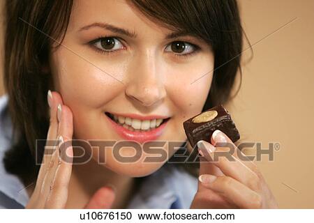 Young woman eating chocolate candy, portrait, close up View Large Photo Image Stock Image - Young woman eating chocolate candy, portrait, close up. Fotosearch