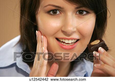 Young woman eating chocolate candy, portrait, close up View Large Photo Image Stock Image - Young woman eating chocolate candy, portrait, close up. Fotosearch