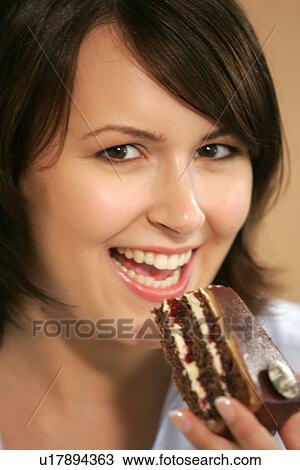 Stock Image - Young woman eating slice of chocolate cake, portrait, close up. Fotosearch