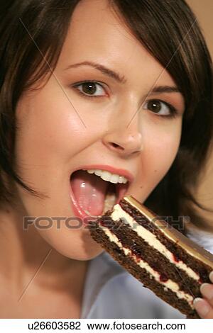Stock Image - Young woman eating slice of chocolate cake, portrait, close up. Fotosearch