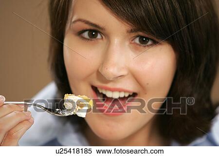 Stock Photography - Young woman eating slice of fruit pie, portrait, close up. Fotosearch