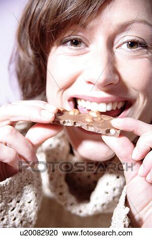 Woman eating piece of chocolate, looking at camera, portrait View Large Photo Image Stock Image - Woman eating piece of chocolate, looking at camera, portrait. Fotosearch
