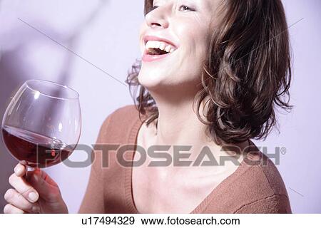 Woman holding glass of red wine, laughing View Large Photo Image Stock Photo - Woman holding glass of red wine, laughing. Fotosearch