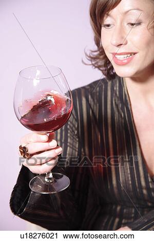 Stock Image - Woman looking at glass of red wine. Fotosearch