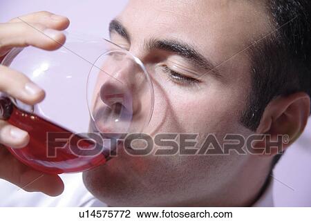 Stock Image - Young man drinking red wine, close up. Fotosearch