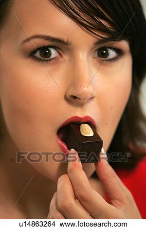 Young woman eating chocolate candy, portrait, close up View Large Photo Image Picture - Young woman eating chocolate candy, portrait, close up. Fotosearch