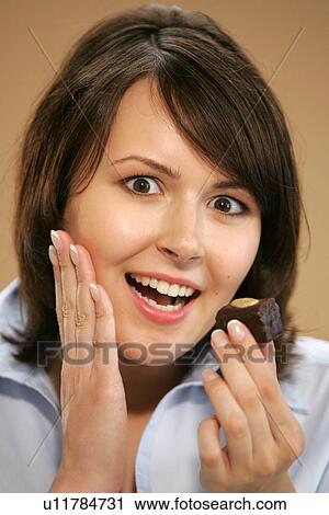 Young woman eating chocolate candy, portrait, close up View Large Photo Image Stock Image - Young woman eating chocolate candy, portrait, close up. Fotosearch