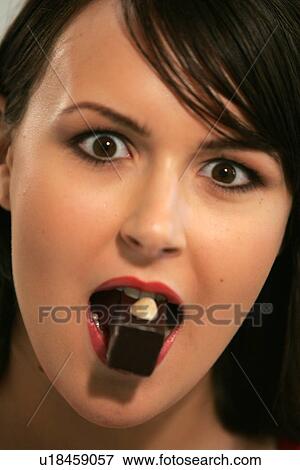 Young woman eating chocolate candy, portrait, close up View Large Photo Image Stock Photo - Young woman eating chocolate candy, portrait, close up. Fotosearch