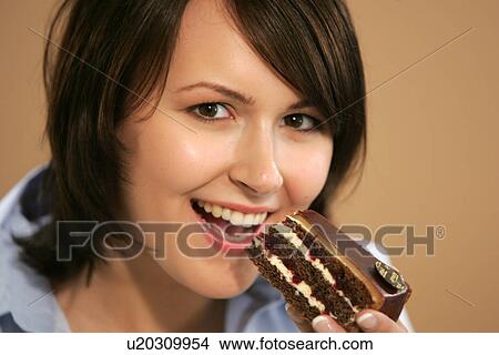 Picture - Young woman eating slice of chocolate cake, portrait, close up. Fotosearch