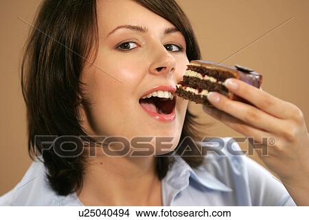 Picture - Young woman eating slice of chocolate cake, portrait, close up. Fotosearch