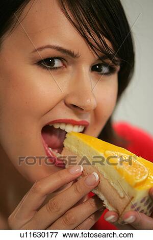 Stock Photo - Young woman eating slice of fruit pie with her fingers, portrait, close up. Fotosearch