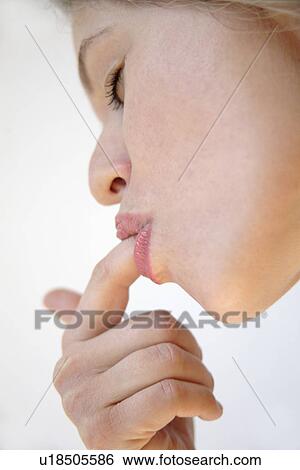Stock Photograph - Young woman licking something off her finger with eyes closed, face profile, close up. Fotosearch