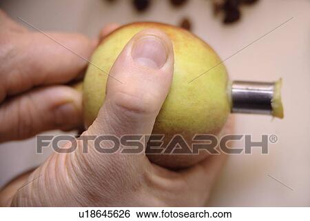 Stock Photograph - Man removes apple core with special kitchen utensil, close up. Fotosearch