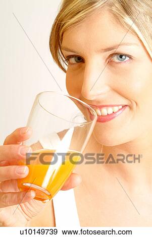 Stock Photo - Portrait of woman drinking orange juice. Fotosearch