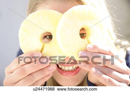Portrait of young woman holding pineapple slices in front of eyes, smiling View Large Photo Image Stock Photo - Portrait of young woman holding pineapple slices in front of eyes, smiling. Fotosearch
