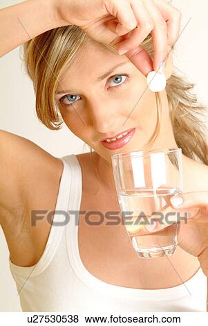Stock Photo - Woman dropping fizzy tablet into glass of water. Fotosearch