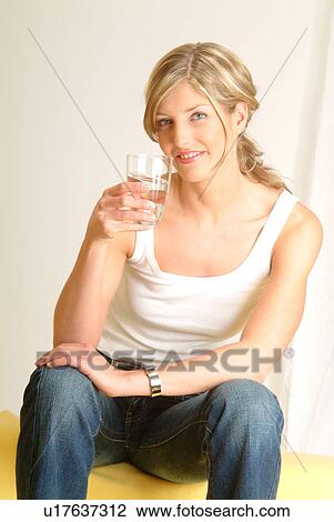 Stock Image - Woman on sofa drinking mineral water. Fotosearch
