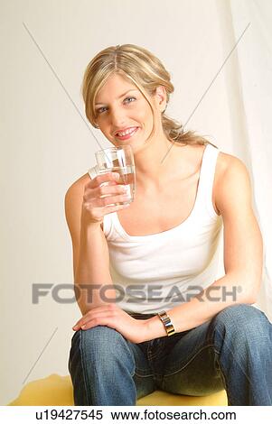 Stock Photography - Woman on sofa drinking mineral water. Fotosearch