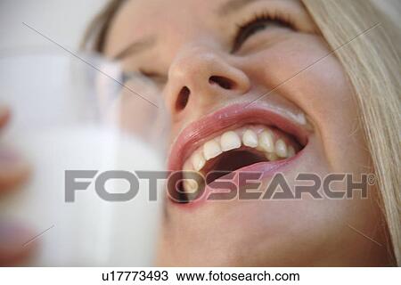 Stock Image - Young blond woman drinking milk from a glass, milksop, close up. Fotosearch