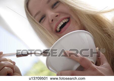Young blond woman eating bowl of cereals, laughing, close up View Large Photo Image Stock Image - Young blond woman eating bowl of cereals, laughing, close up. Fotosearch