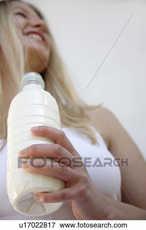 Young blond woman holding milk bottle, view from below View Large Photo Image Stock Photo - Young blond woman holding milk bottle, view from below. Fotosearch