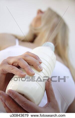 Young blond woman holding milk bottle, view from below View Large Photo Image Stock Photo - Young blond woman holding milk bottle, view from below. Fotosearch