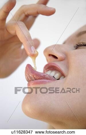 Young blond woman licking honey off her finger, side view, close up View Large Photo Image Stock Photo - Young blond woman licking honey off her finger, side view, close up. Fotosearch