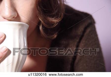 Stock Photograph - Young woman drinking from cup of tea, close up. Fotosearch