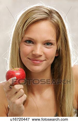 Young woman with long blond hair eating an apple, portrait View Large Photo Image Stock Photo - Young woman with long blond hair eating an apple, portrait. Fotosearch