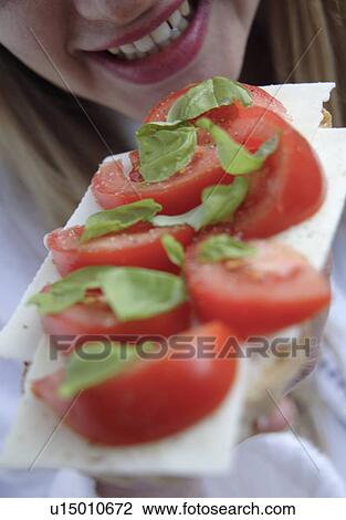 Woman eating bread with cheese, tomato and basil, close up View Large Photo Image Stock Image - Woman eating bread with cheese, tomato and basil, close up. Fotosearch