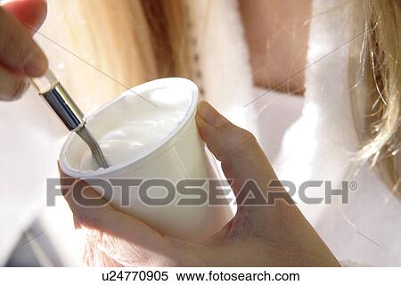 Stock Photography - Woman eating yogurt, close up. Fotosearch