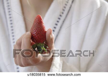 Stock Photography - Woman holding whole strawberry, close up. Fotosearch