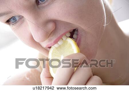 Young blond woman biting in slice of lemon, close up View Large Photo Image Stock Image - Young blond woman biting in slice of lemon, close up. Fotosearch